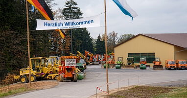 Blick auf Maschinenhalle mit davor ausgestellten Fahrzeugen