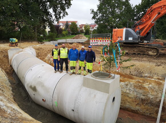 Arbeiter stehen auf Kanalrohren in einer Grube